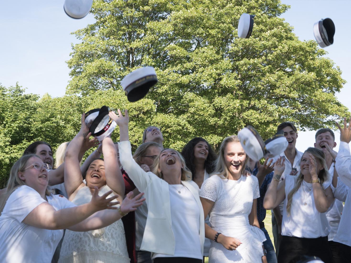 EUX Business studenter kaster huer op i luften ude i parken