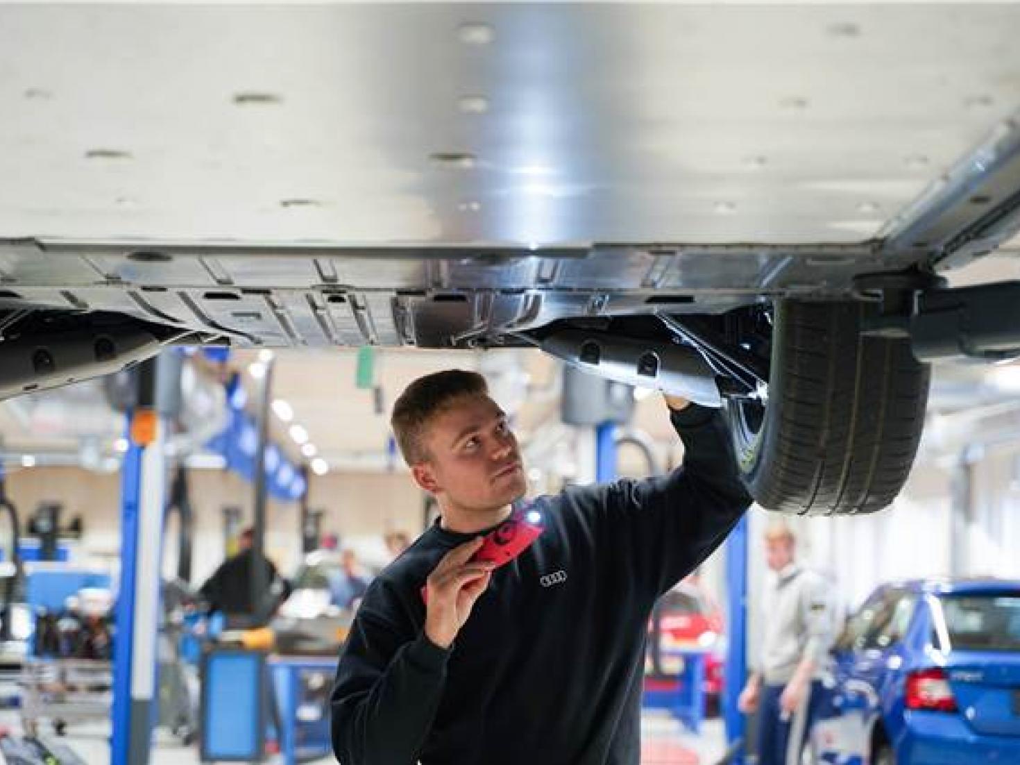 Personvognsmekaniker undersøger bunden af en bil 