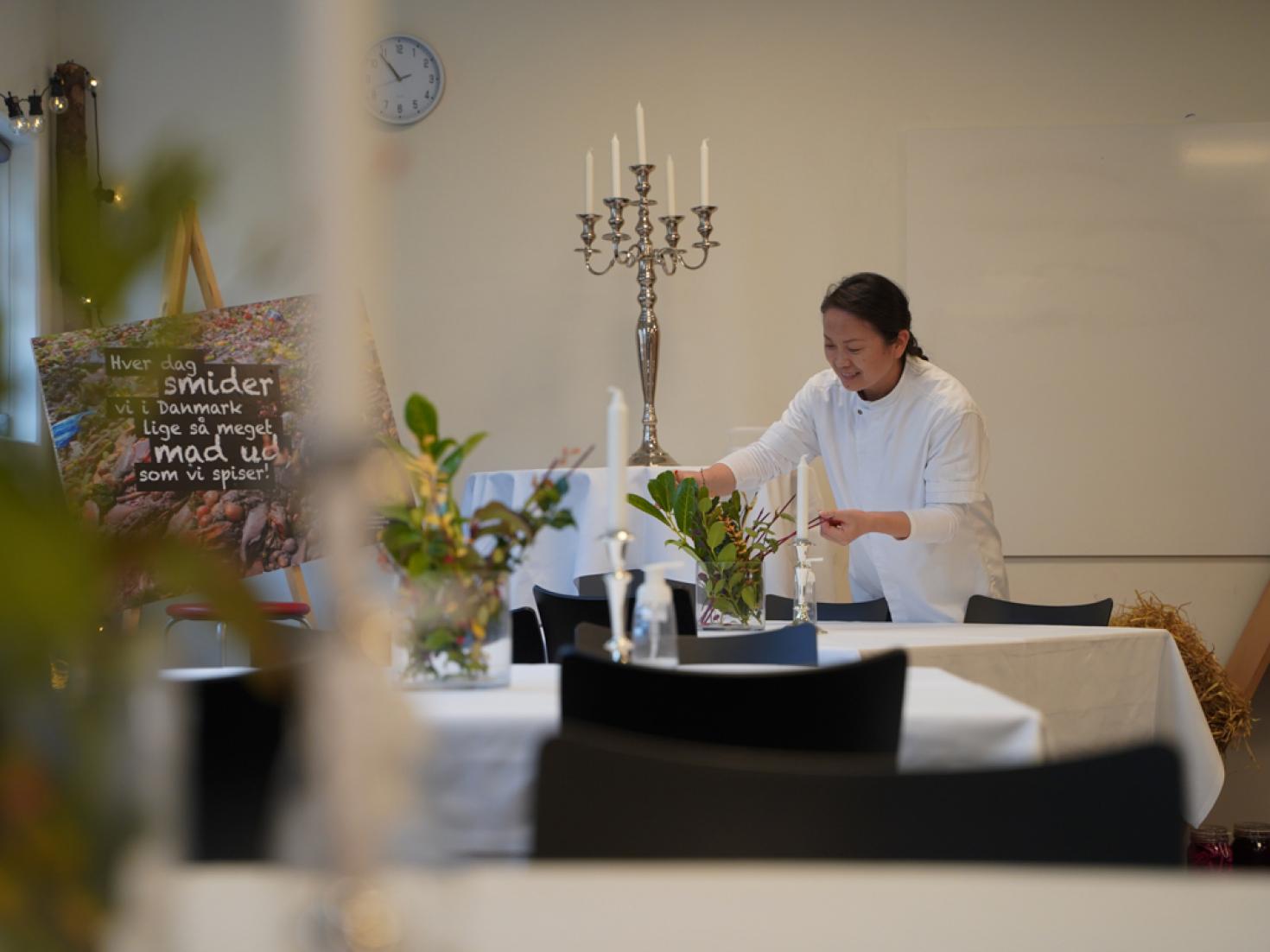 Tjener dækker bord i lokale 