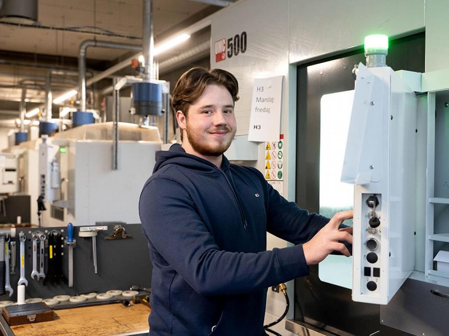 Ung mand elev står ved CNC maskine 