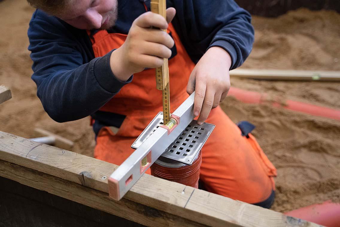 struktør arbejder med rør i sandgrav